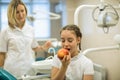 Woman dentist gives apple for smiling teenage girl