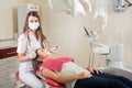 Woman dentist in her office treating female patient