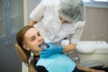 Woman dentist puts on a guy patient a mouth guard a removable orthodontic teeth alignment and correction trainer appliance in de