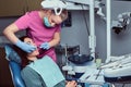 Dentist is treating female patient which is sitting in a dental chair in the clinic. Royalty Free Stock Photo