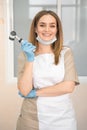 Woman dermatologist with dermatoscope in uniform and gloves in doctor office, examination room in clinic