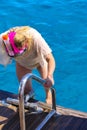 The woman descends the ladder to the transparent turquoise sea