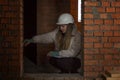 A woman designer-architect in a white construction helmet takes measurements of the brick walls of a house. Repair and interior