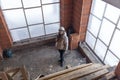 A woman designer-architect in a white construction helmet takes measurements of the brick walls of an unfinished house. Repair and