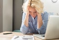 Woman at desk Stares at Calculator Holding Head in Hands Royalty Free Stock Photo