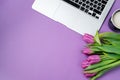 Woman desktop with Laptop, morning coffee and tulips on violet b