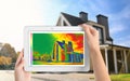 Woman detecting heat loss in house using thermal viewer on tablet. Energy efficiency
