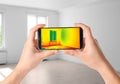 Woman detecting heat loss in room using thermal viewer on smartphone