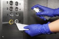 Woman with detergent spray and paper napkin cleaning elevator`s panel, closeup