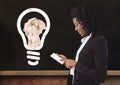 Woman on device standing next to light bulb with crumpled paper ball in front of blackboard Royalty Free Stock Photo
