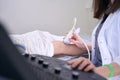 Woman diagnostician conducts an ultrasound procedure of patients knee joint