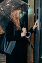 Woman dialing a number on the on video intercom at entrance of apartment building in the night Royalty Free Stock Photo