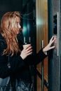 Woman dialing a number on the on video intercom at entrance of apartment building in the night Royalty Free Stock Photo