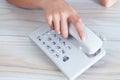 A woman dials a number on a home wired phone