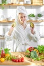 Female on diet. Young and happy woman in bathrobe showing green fresh ingredients indoors