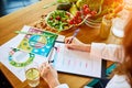 Woman dietitian in medical uniform with tape measure working on a diet plan sitting with different healthy food ingredients in the