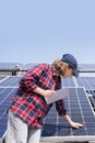 Woman with digital tablet touching solar panel