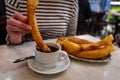 A woman dipping a churro into chocolate