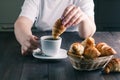 Woman dipping croissant in coffee