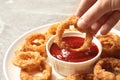 Woman dipping crunchy fried onion ring
