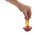 Woman dipping delicious chip into ketchup on white background, closeup