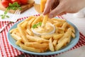 Woman dipping delicious French fries into cheese sauce at white table, closeup Royalty Free Stock Photo