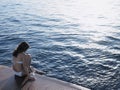 Woman Dipping Foot In Sea While Sitting On Yacht's Floorboard