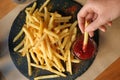 Woman dipping French fries into red sauce in cafe Royalty Free Stock Photo