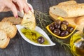 Woman dipping fresh bread into tasty olive oil with spices in bowl. Olive oil bread dip.