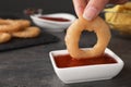 Woman dipping onion ring into hot chili sauce in bowl