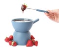 Woman dipping strawberry into fondue pot with chocolate on white background