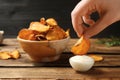 Woman dipping sweet potato chip into sauce on table