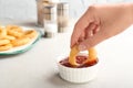 Woman dipping tasty onion ring into bowl