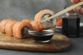 Woman dipping tasty sushi roll with salmon into soy sauce at grey table, closeup Royalty Free Stock Photo