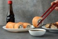 Woman dipping tasty sushi roll with salmon into soy sauce at grey table, closeup Royalty Free Stock Photo