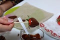 A woman dips strawberries in black melted chocolate. Cooking strawberries glazed in chocolate