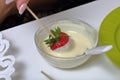 A woman dips strawberries in white melted chocolate. Cooking strawberries glazed in chocolate