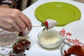 A woman dips strawberries in white melted chocolate. Cooking strawberries glazed in chocolate