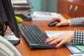 A woman director working in an office is sitting at a table, typing on a keyboard, checking documents. Royalty Free Stock Photo