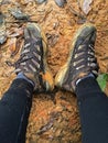 Woman with dirty brown hiking shoes resting on wet muddy area