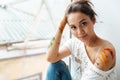 Woman dirty with colorful paints sitting near the window