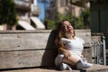 Woman with disability, reduced mobility and small stature sitting on a wooden bench, happy and relaxed sunbathing. Concept