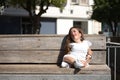 Woman with disability, reduced mobility and small stature sitting on a wooden bench, happy and relaxed sunbathing. Concept