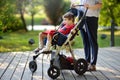 Woman with disabled girl in a wheelchair walking in the Park summer. Child cerebral palsy. Family with disabled kid Royalty Free Stock Photo