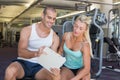 Woman discussing her performance on clipboard with trainer at gym