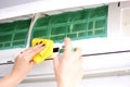 Woman disinfecting the indoor unit of air conditioner