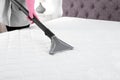 Woman disinfecting mattress with vacuum cleaner, closeup.