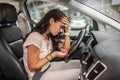 Woman in dispair holds her head sitting on driver& x27;s seat with a handfull of pills in her other hand