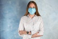 Woman with disposable mask on face against blue background