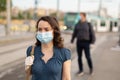 Woman in disposable mask at tram stop